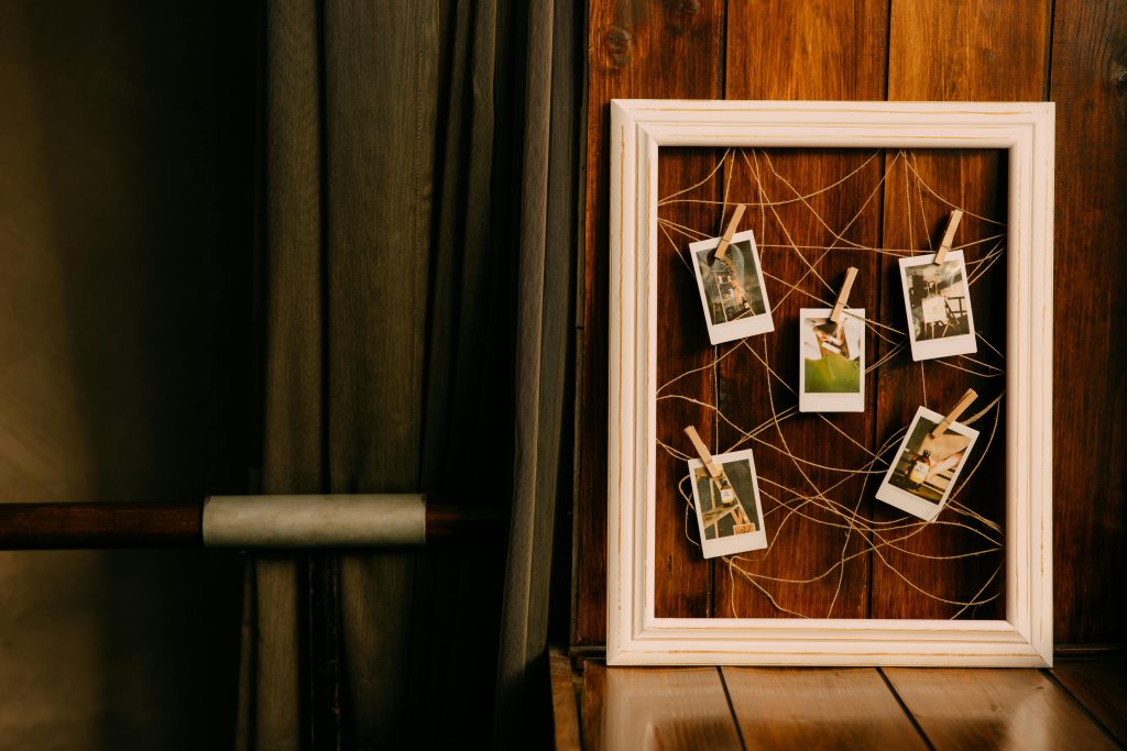 A rustic wooden frame holds Polaroid photos, perfect for vintage decor lovers.