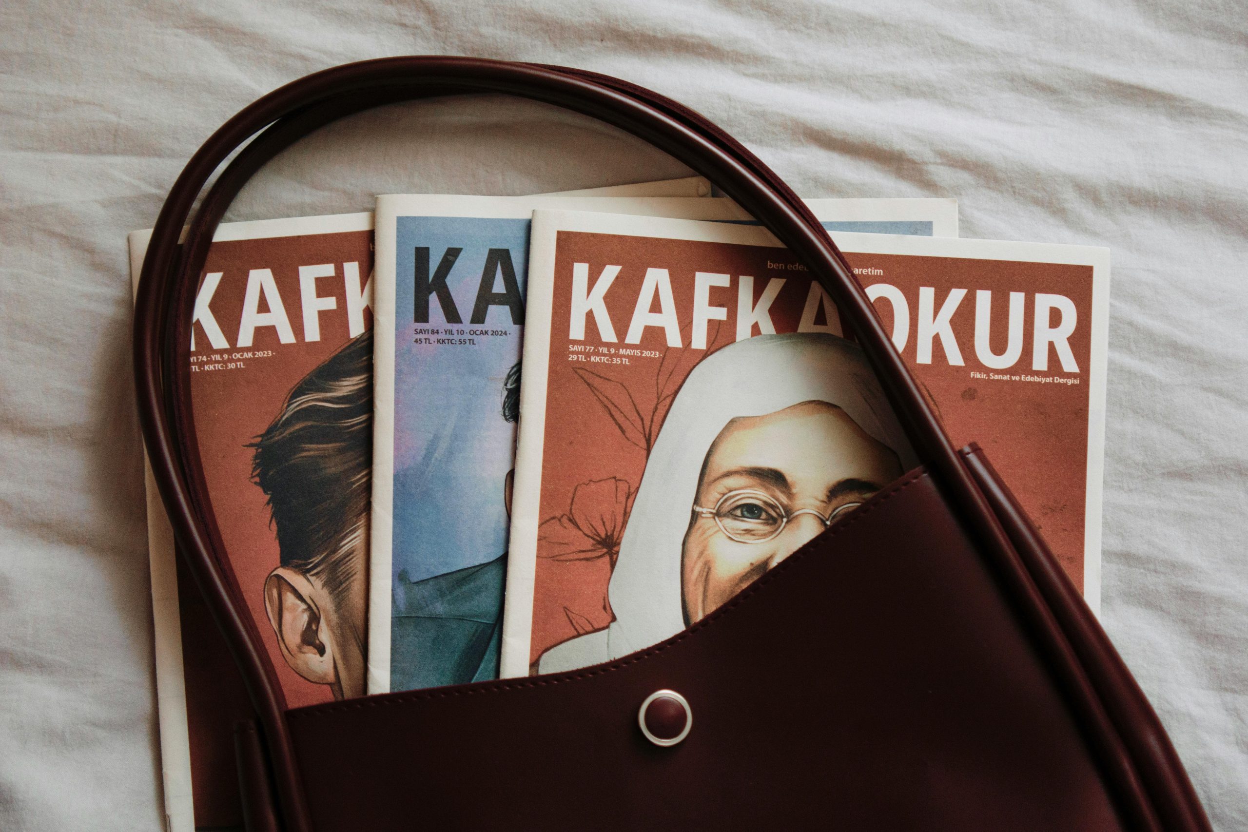 Elegant leather handbag showcasing Kafa magazines with artistic covers. Ideal for lifestyle and fashion themes.