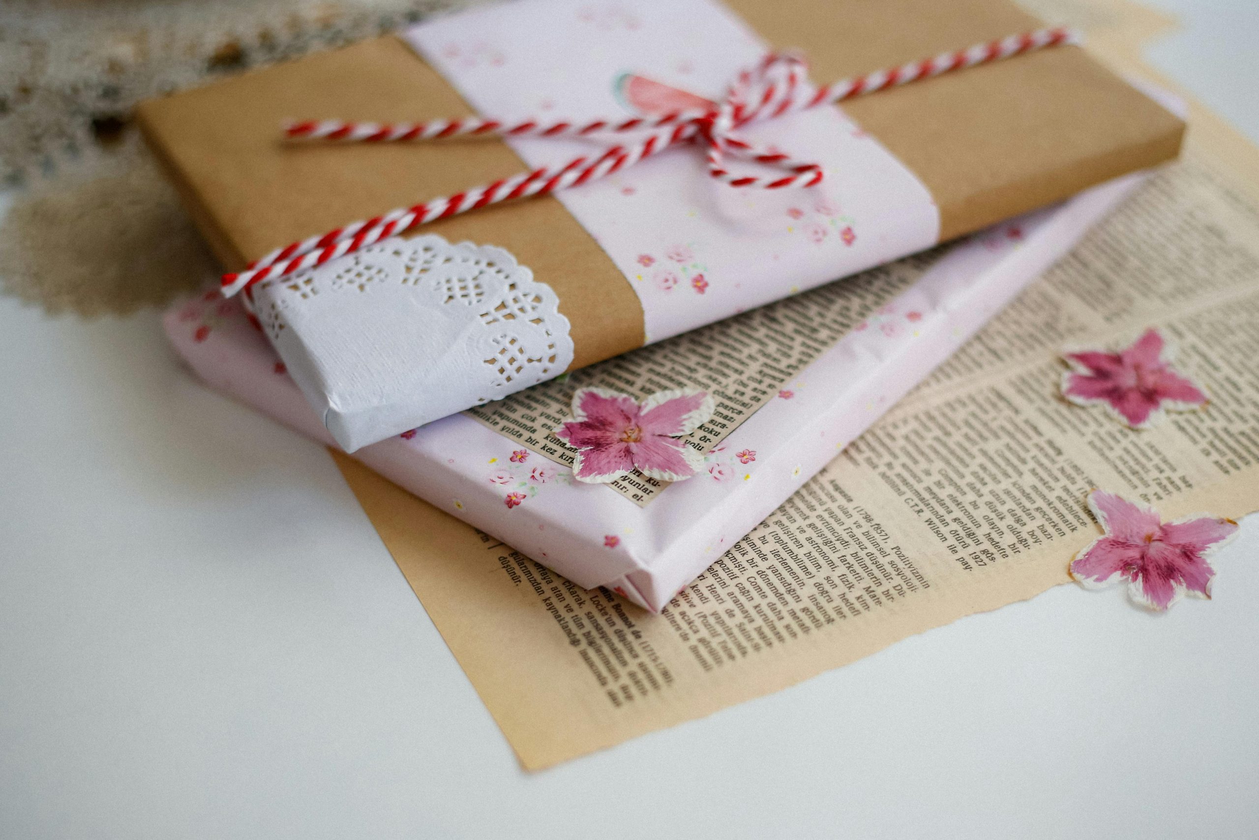 Charming floral gift boxes decorated with pink flowers and twine on a vintage paper background.