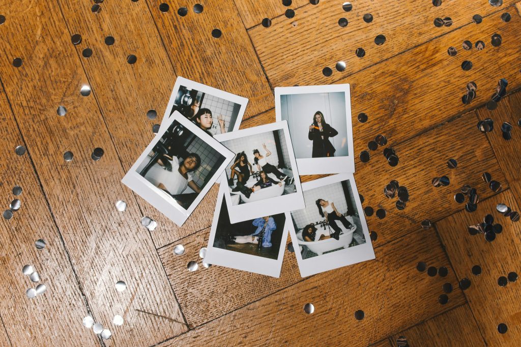A collection of polaroid pictures scattered with confetti on a wooden floor.
